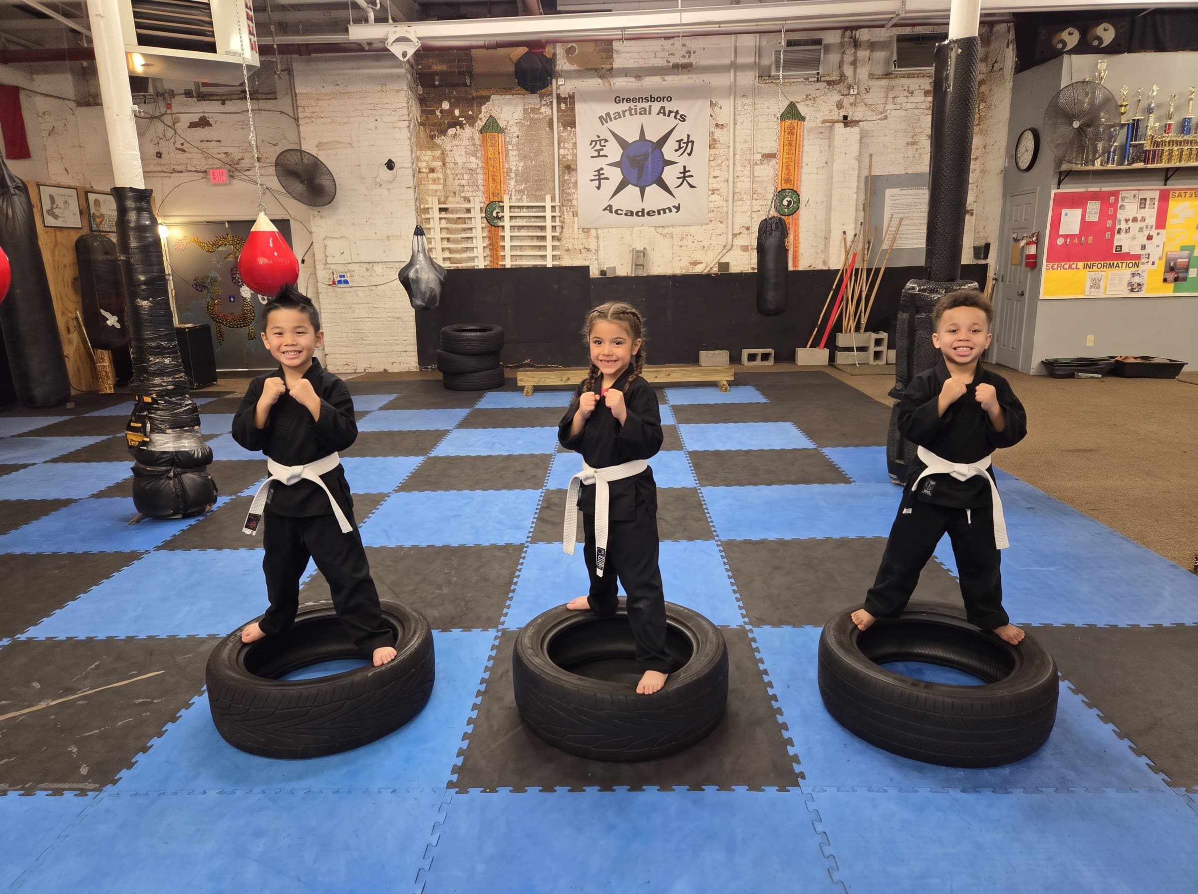 Three young students balancing on tires in the training hall