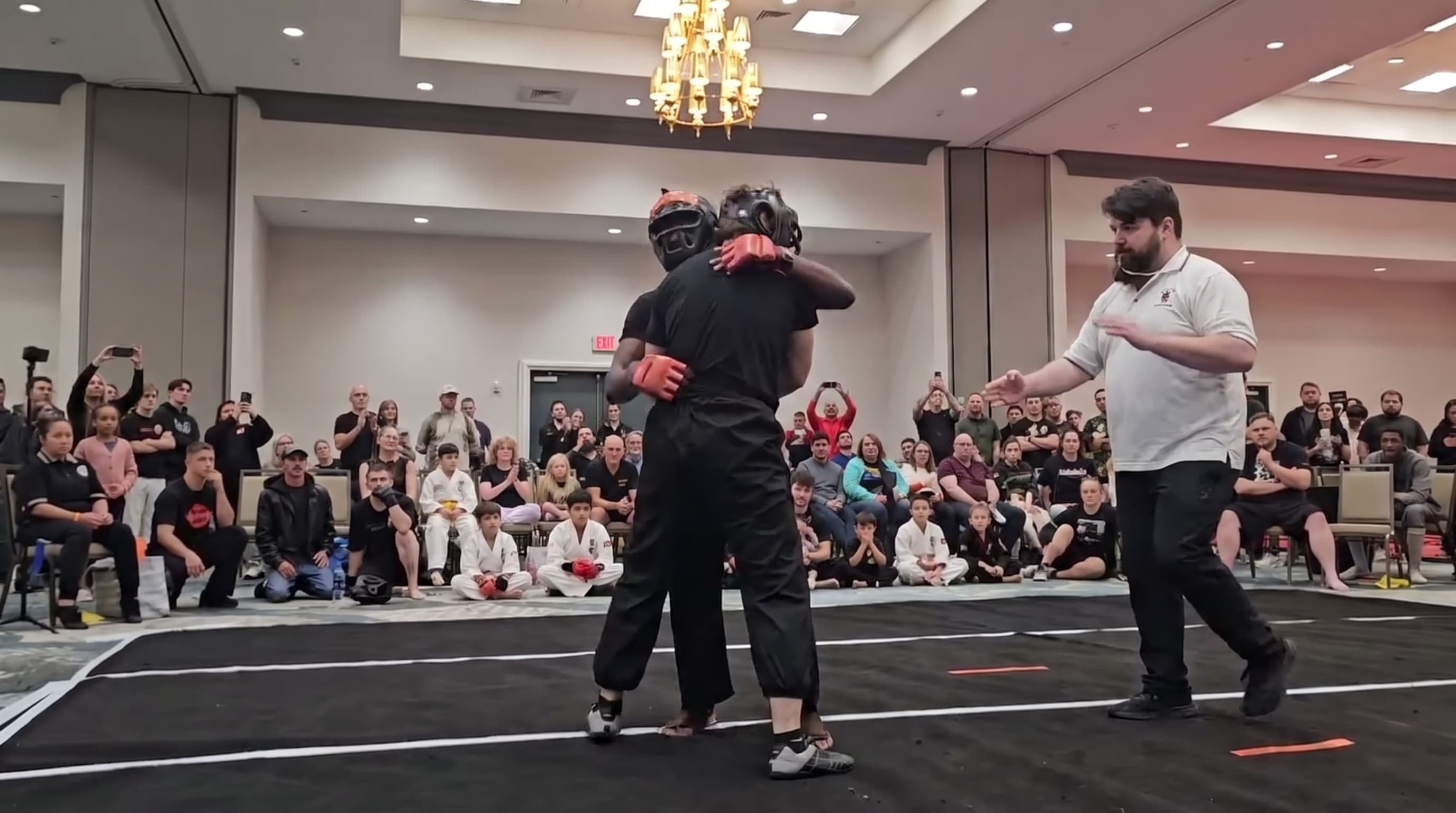 Two adult students sparring with headgear in front of a crowd